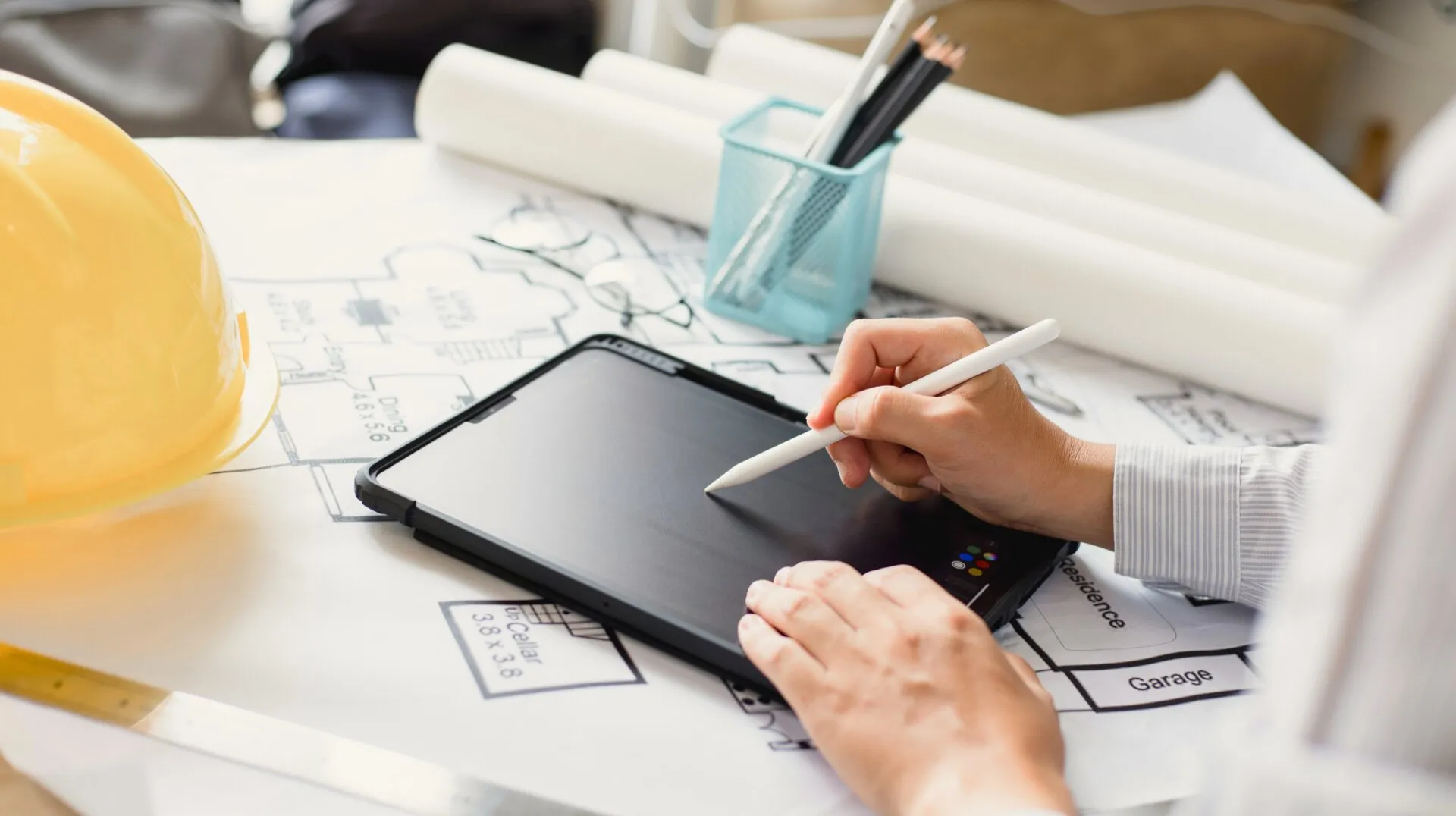 Architekt / Ingenieur vor einer Bauskizze und einem Tablet für die digitale Elektroplanung im Hausbau.