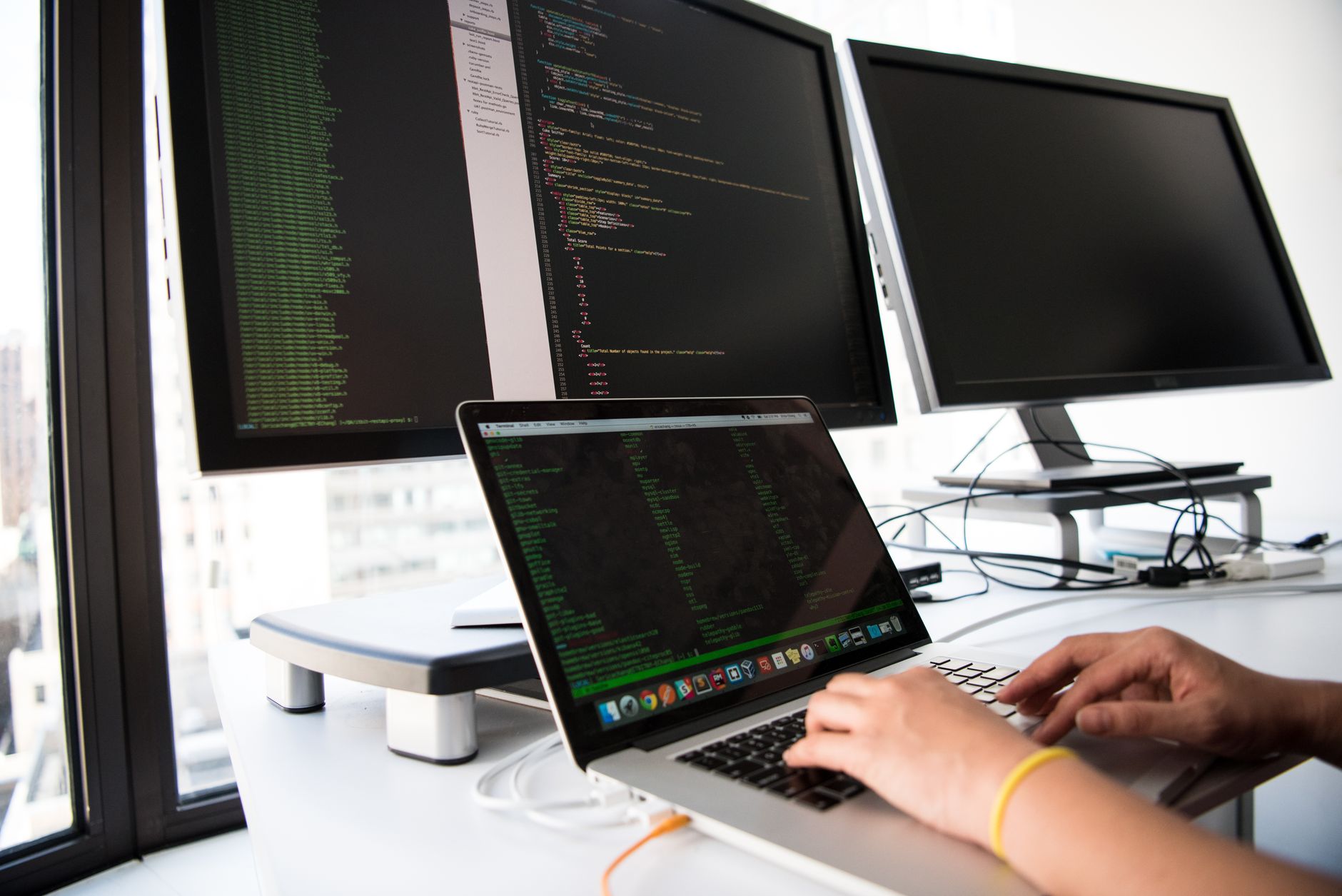 Entwickler liest Code und Log-Ausgaben auf zwei Monitoren — die Datenbasis der technischen Due Diligence