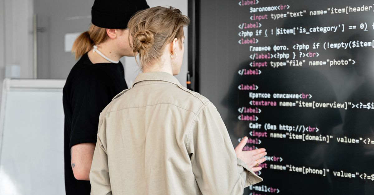 Zwei Entwickler analysieren Code auf einem großen Bildschirm: Förderfähig ist Softwareentwicklung nur bei echtem technischen Risiko